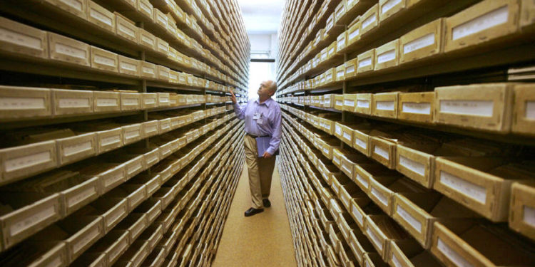 Gary Mokotoff, un genealogista judío de Nueva Jersey, echa un vistazo a los registros de nombres en el Servicio de Rastreo Internacional en Bad Arolsen, Alemania central. | Archivos: AP / Michael Probst