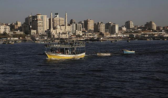 Los barcos pesqueros palestinos navegan hacia las aguas del mar Mediterráneo en la ciudad de Gaza, el lunes 9 de julio de 2018, con los edificios de la ciudad de Gaza vistos como fondo. (Foto AP / Adel Hana)
