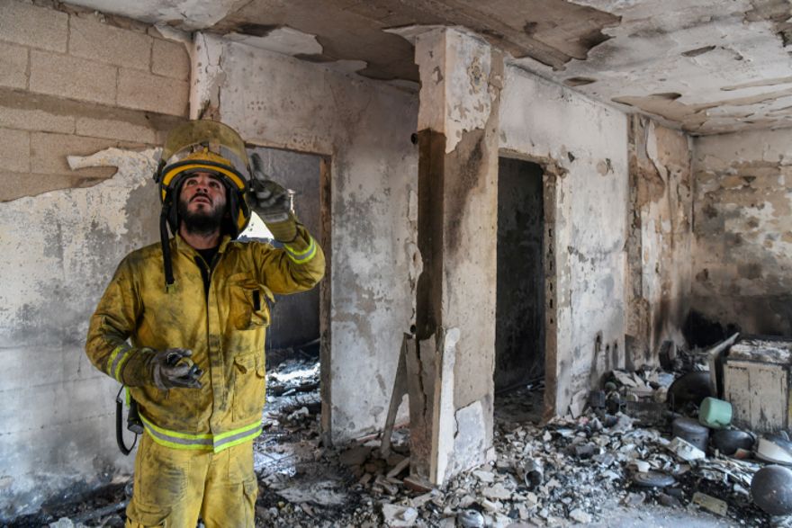 Los bomberos observan los daños causados ​​por un incendio en Kibbutz Harel, el 24 de mayo de 2019. (Noam Revkin Fenton / Flash90)