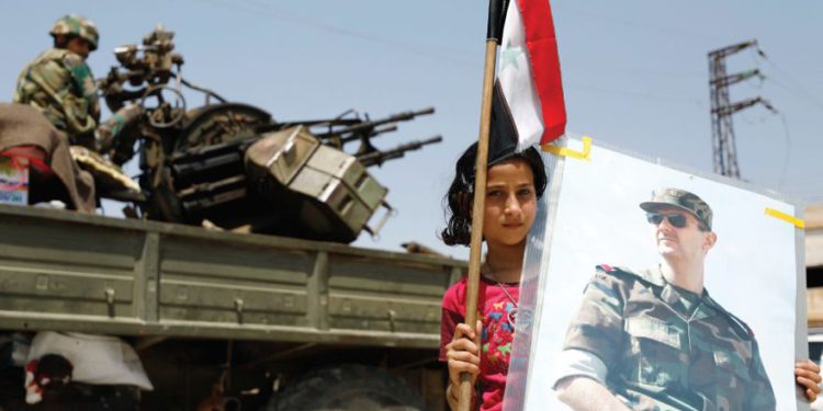 Una NIÑA sostiene una imagen del presidente sirio Bashar Assad .. (crédito de foto: REUTERS)