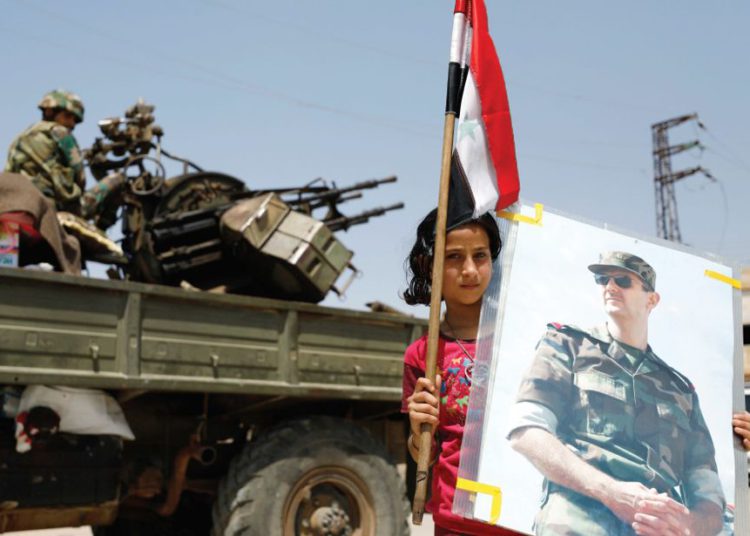 Una NIÑA sostiene una imagen del presidente sirio Bashar Assad .. (crédito de foto: REUTERS)
