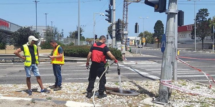 Los trabajadores del ministerio del medio ambiente de Israel rocían agua en las alcantarillas de un área comercial que intenta dispersar el gas explosivo que se filtró de las refinerías químicas de la Bahía de Haifa, el 18 de mayo de 2019. (Ministerio de Protección Ambiental)