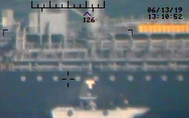 Esta imagen, publicada por el Departamento de Defensa de los EE. UU. El lunes 17 de junio de 2019 y tomada de un helicóptero de la Armada de los EE. UU., Muestra lo que la Armada dice que son miembros del Cuerpo de la Guardia Revolucionaria Islámica, que están retirando una mina de laca sin explotar del M / T Kokuka. Valiente. (Departamento de Defensa de los Estados Unidos a través de AP)
