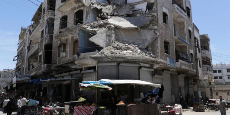 ARCHIVO - La gente pasa frente a un edificio dañado en la ciudad de Idlib, Siria, el 25 de mayo de 2019.