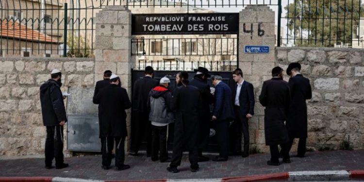 Hombres ultraortodoxos en la puerta cerrada de la Tumba de los Reyes, propiedad y administrada por el Consulado de Jerusalem en el este de Jerusalem, el 24 de enero de 2019. (THOMAS COEX / AFP)