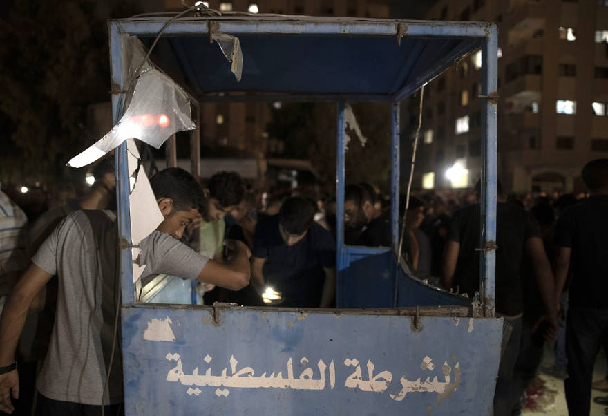 Los palestinos revisan una cabina de policía dañada luego de una explosión dirigida a un puesto de control policial de Hamás en la ciudad de Gaza, el martes 27 de agosto de 2019. (Foto AP / Khalil Hamra)