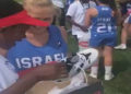 Los jugadores de lacrosse de Israel y Kenia se abrazan después de que el equipo israelí regale a sus oponentes zapatos nuevos con tacos, 7 de agosto de 2019 (captura de pantalla de video)
