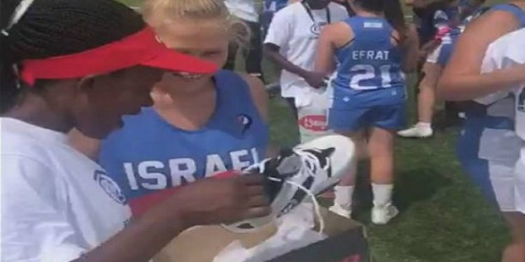 Los jugadores de lacrosse de Israel y Kenia se abrazan después de que el equipo israelí regale a sus oponentes zapatos nuevos con tacos, 7 de agosto de 2019 (captura de pantalla de video)