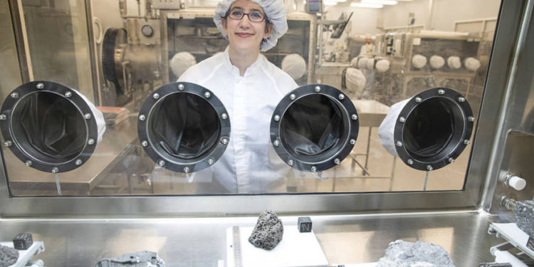 La reportera de astronomía Science News Lisa Grossman visita el prístino laboratorio de muestras en el Centro Espacial Johnson de la NASA en Houston en marzo. La vitrina contiene rocas recolectadas durante el Apolo 15 y 16. El trozo de basalto volcánico de 1.5 kilogramos en el centro tiene 3.400 millones de años.