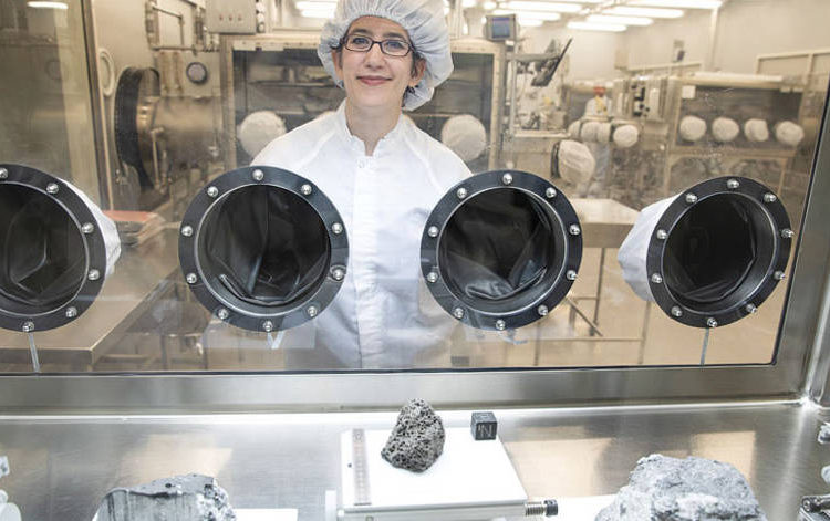 La reportera de astronomía Science News Lisa Grossman visita el prístino laboratorio de muestras en el Centro Espacial Johnson de la NASA en Houston en marzo. La vitrina contiene rocas recolectadas durante el Apolo 15 y 16. El trozo de basalto volcánico de 1.5 kilogramos en el centro tiene 3.400 millones de años.