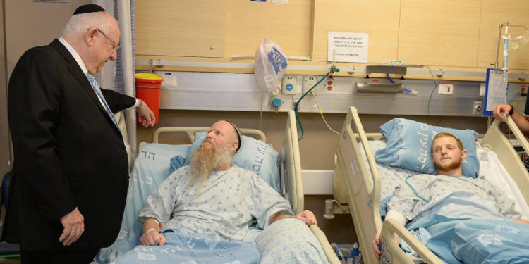 El presidente Reuven Rivlin visita al rabino Eitan Shnerb, cuya hija Rina fue asesinada en un atentado terrorista en Cisjordania, en el Hospital Hadassah Ein Kerem en Jerusalén el 26 de agosto de 2019. (Mark Neiman / GPO)