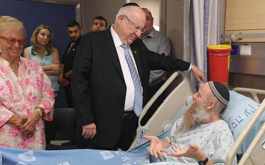 El presidente Reuven Rivlin visita al rabino Eitan Shnerb, cuya hija Rina fue asesinada en un atentado terrorista en Cisjordania, en el Hospital Hadassah Ein Kerem en Jerusalén el 26 de agosto de 2019. (Mark Neiman / GPO)