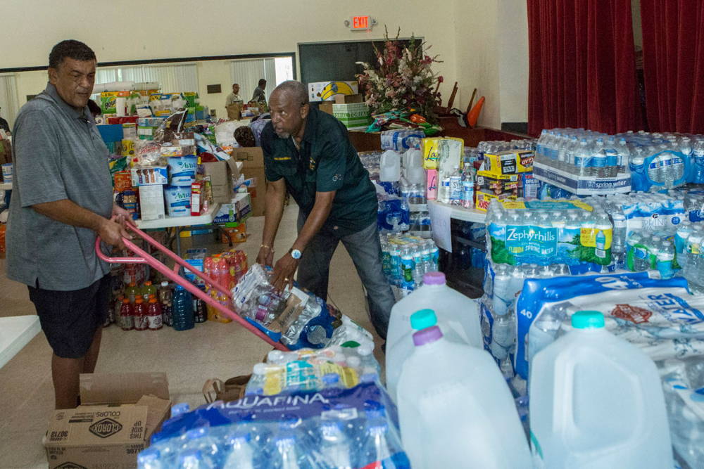 Dos voluntarios juntan agua y artículos de primera necesidad para los afectados por Dorian (AP)