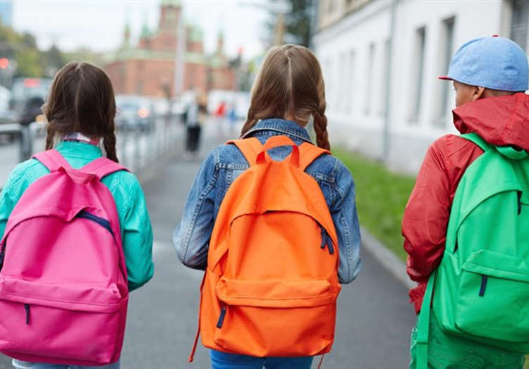 Escolares caminando con mochilas - iStock