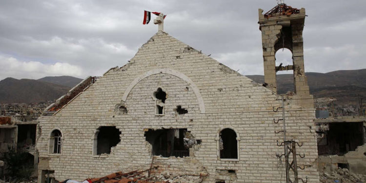 Una bandera siria ondea sobre la dañada iglesia ortodoxa romana de santa maría en la ciudad turística de montaña de zabadani en el campo de damasco | Archivos: AP / Hassan Ammar