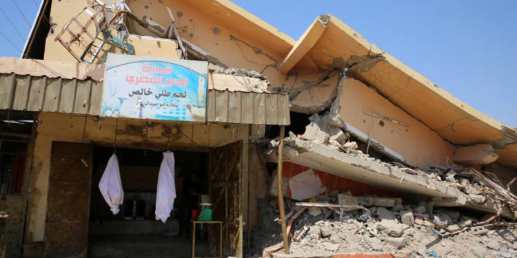 Una fotografía tomada el 25 de agosto de 2019 muestra una tienda destruida debajo de un edificio muy dañado en Baiji, una región rica en petróleo devastada por la lucha contra el grupo del Estado Islámico en 2014. (SABAH ARAR / AFP)