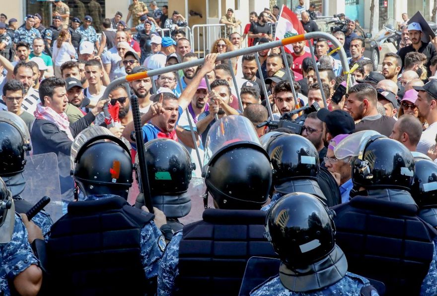 Manifestantes libaneses se enfrentan con policías antidisturbios mientras intentan romper las barreras de seguridad frente a la oficina del gabinete durante una manifestación en el centro de la Plaza Mártir de Beirut el 29 de septiembre de 2019. (ANWAR AMRO / AFP)