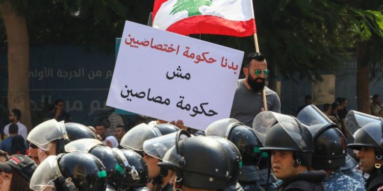 Un manifestante libanés sostiene la bandera nacional y una pancarta que dice en árabe "Queremos un gobierno de especialistas, no un gobierno de tontos" durante una manifestación en el centro de la Plaza Mártir de Beirut el 29 de septiembre de 2019. (ANWAR AMRO / AFP)