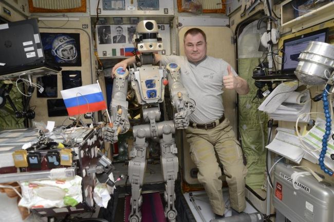El robot humanoide Skybot F-850 de Rusia sostiene una bandera rusa con el cosmonauta Alexey Ovchinin para una foto en el módulo de servicio Zvezda de la Estación Espacial Internacional en esta foto publicada el sept. (Crédito de la imagen: Roscosmos a través de Twitter )