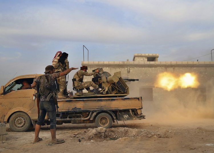 En esta foto del 14 de octubre de 2019, combatientes de la oposición siria respaldados por Turquía disparan una ametralladora pesada contra combatientes kurdos, en la región norteña siria de Manbij. (Foto AP)