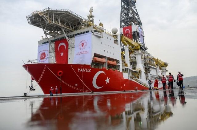 Los periodistas caminan junto al barco de perforación 'Yavuz' programado para buscar petróleo y gas en Chipre, en el puerto de Dilovasi, en las afueras de Estambul, el 20 de junio de 2019. (Bulent Kilic / AFP)