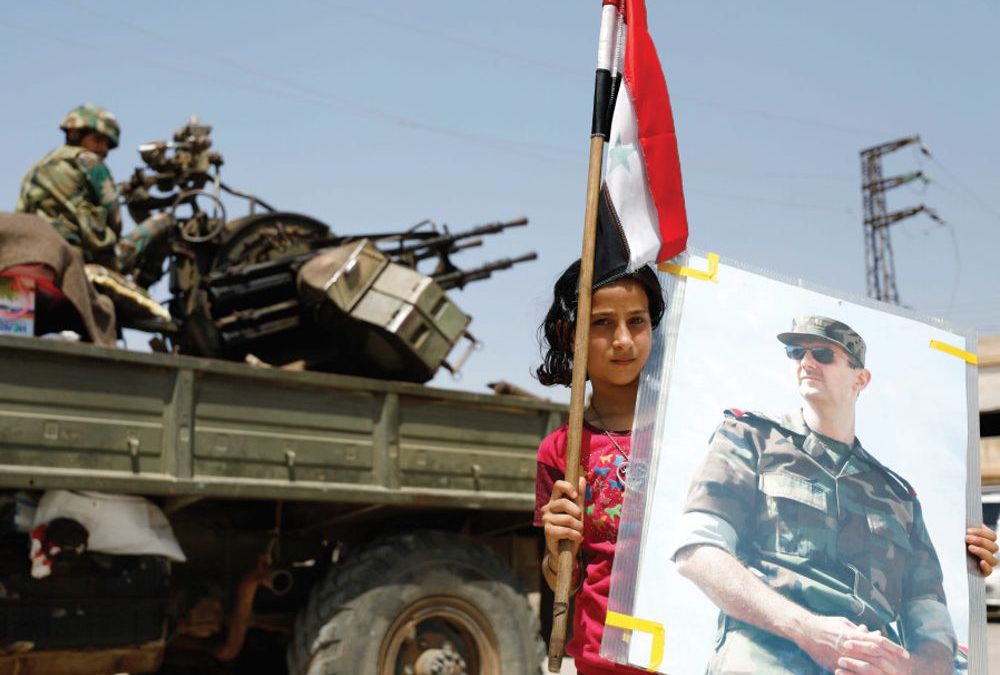 Una niña sostiene una imagen del presidente sirio Bashar Assad .. (crédito de la foto: REUTERS)