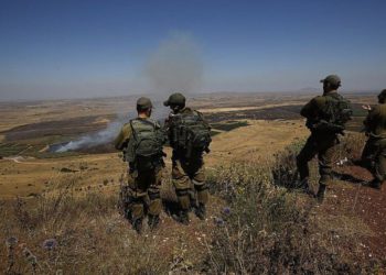 Ilustrativo: los soldados israelíes en una base del ejército en los Altos del Golán miran a través de la frontera con Siria el 7 de julio de 2018. (Foto de AFP / Jalaa Marey)