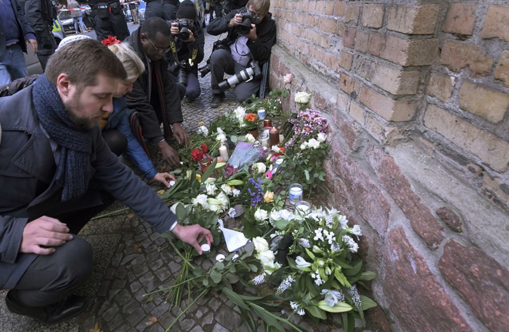 La gente coloca flores frente a una sinagoga en Halle, Alemania, 10 de octubre de 2019 (AP Photo / Jens Meyer)