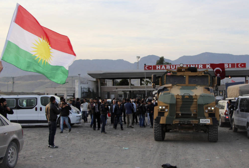 Un hombre agita una bandera de Kurdistán mientras un camión militar turco escolta a un convoy de vehículos peshmerga en la puerta fronteriza de Habur, que separa Turquía de Irak, cerca de la ciudad de Silopi, en el sureste de Turquía. (Crédito de la foto: REUTERS)