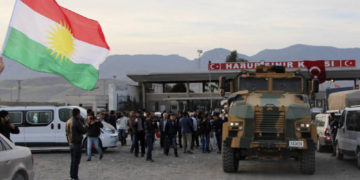 Un hombre agita una bandera de Kurdistán mientras un camión militar turco escolta a un convoy de vehículos peshmerga en la puerta fronteriza de Habur, que separa Turquía de Irak, cerca de la ciudad de Silopi, en el sureste de Turquía. (Crédito de la foto: REUTERS)