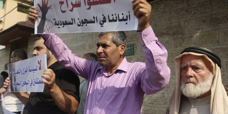 Las familias de palestinos detenidos en las cárceles de Arabia Saudita sostienen pancartas en árabe que dicen: "Liberen a nuestros hijos en las cárceles sauditas y no por la política de aislamiento y tortura para los prisioneros en las cárceles sauditas" durante una protesta, frente a la Internacional Comité de la oficina de la Cruz Roja, en Gaza, 16 de octubre de 2019. (Foto AP / Adel Hana)