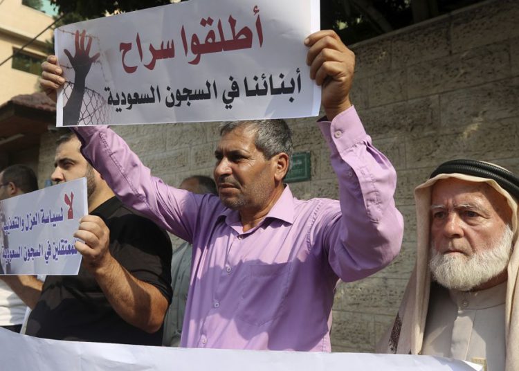 Las familias de palestinos detenidos en las cárceles de Arabia Saudita sostienen pancartas en árabe que dicen: "Liberen a nuestros hijos en las cárceles sauditas y no por la política de aislamiento y tortura para los prisioneros en las cárceles sauditas" durante una protesta, frente a la Internacional Comité de la oficina de la Cruz Roja, en Gaza, 16 de octubre de 2019. (Foto AP / Adel Hana)