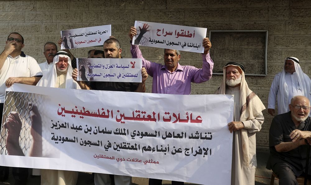 Las familias de los palestinos detenidos en las cárceles de Arabia Saudita sostienen pancartas en árabe que dicen: "Liberen a nuestros hijos en las cárceles sauditas" y "No por la política de aislamiento y tortura para los prisioneros en las cárceles sauditas" durante una protesta frente Oficina del Comité Internacional de la Cruz Roja en Gaza, 16 de octubre de 2019. (Foto AP / Adel Hana)