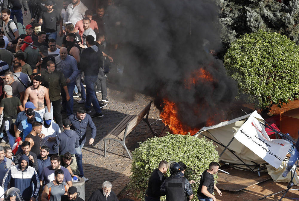 Los partidarios de Hezbolá, a la izquierda, queman tiendas de campaña en el campamento de protesta establecido por manifestantes antigubernamentales cerca del palacio de gobierno, en Beirut, Líbano, el 29 de octubre de 2019 (Foto AP / Hussein Malla)