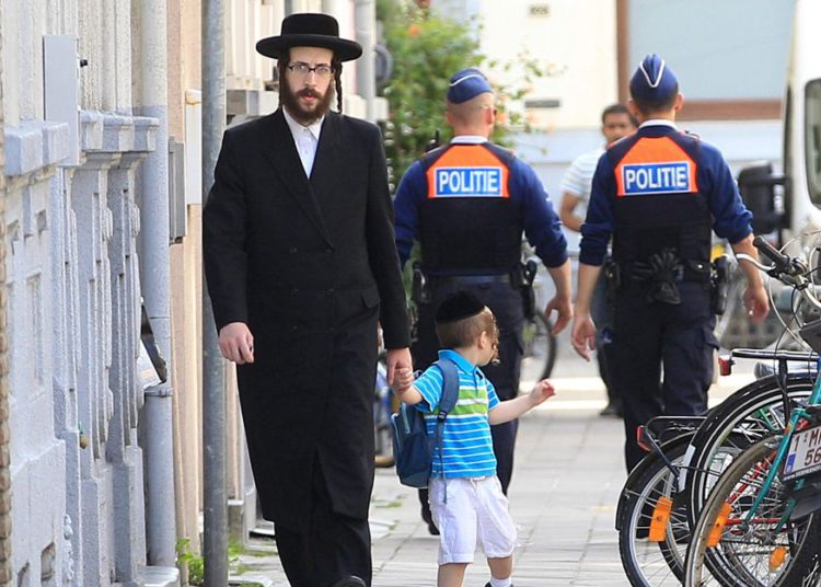 Ilustrativo: un judío ortodoxo y un niño pasan a dos policías en Amberes, Bélgica, el 25 de mayo de 2014. (Foto AP / Yves Logghe)
