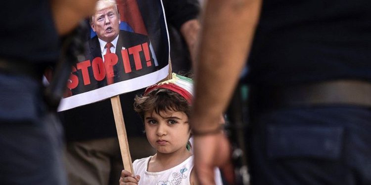 Una niña lleva una pancarta del presidente de Estados Unidos, Donald Trump, mientras marchan en la capital chipriota de Nicosia el 12 de octubre de 2019, para protestar contra la ofensiva turca en las ciudades controladas por los kurdos en el norte de Siria. (Iakovos Hatzistavrou / AFP)