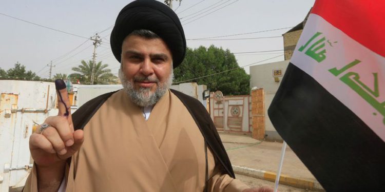 El clérigo chiíta iraquí Muqtada al-Sadr muestra su dedo manchado de tinta después de emitir su voto en un colegio electoral durante las elecciones parlamentarias en Najaf, Iraq, el 12 de mayo. (Crédito de la foto: REUTERS)