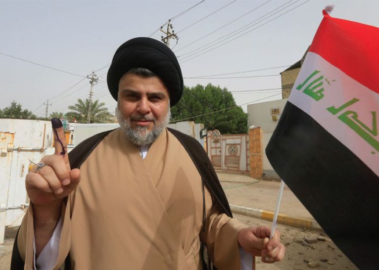 El clérigo chiíta iraquí Muqtada al-Sadr muestra su dedo manchado de tinta después de emitir su voto en un colegio electoral durante las elecciones parlamentarias en Najaf, Iraq, el 12 de mayo. (Crédito de la foto: REUTERS)