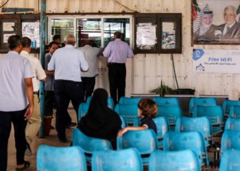Los palestinos esperan mientras otros presentan documentos de viaje a los oficiales de la Autoridad Palestina en el Cruce Erez con Israel cerca de Beit Hanoun en el norte de la Franja de Gaza el 27 de agosto de 2018. (AFP Photo / Mahmud Hams)