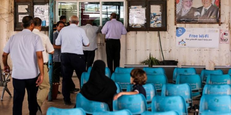 Los palestinos esperan mientras otros presentan documentos de viaje a los oficiales de la Autoridad Palestina en el Cruce Erez con Israel cerca de Beit Hanoun en el norte de la Franja de Gaza el 27 de agosto de 2018. (AFP Photo / Mahmud Hams)