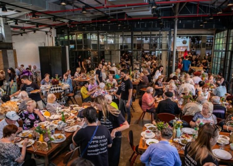 Los sobrevivientes y los invitados comen juntos en el evento de Rosh Hashaná organizado por la Asociación de Ayuda Inmediata para los Sobrevivientes del Holocausto. (Crédito de la foto: GAL HAIM)