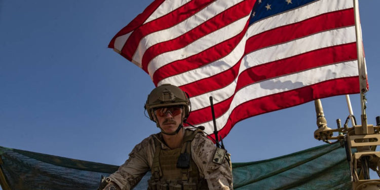 Un soldado se sienta encima de un vehículo militar estadounidense que pasa por la ciudad siria del noreste de Qahtaniyah, en la frontera con Turquía, el 31 de octubre de 2019 (Delil SOULEIMAN / AFP