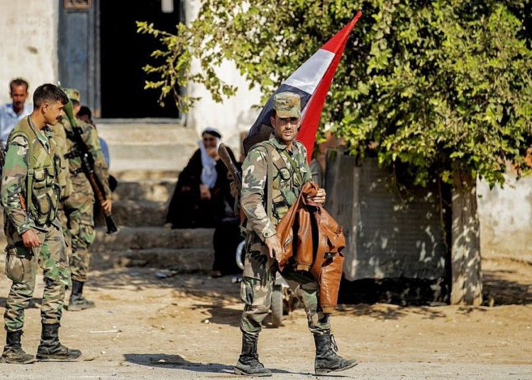 Las fuerzas del régimen sirio son representadas mientras patrullan una calle en la entrada occidental de la ciudad de Tal Tamr, en el campo de la provincia de Hasakeh, en el noreste de Siria, el 14 de octubre de 2019. (Delil Souleiman / AFP)
