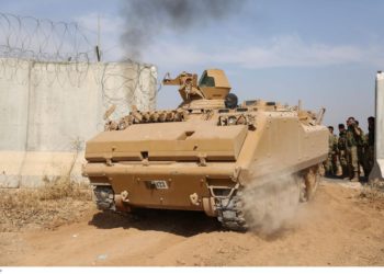 Combatientes sirios pro-turcos conducen un vehículo blindado de transporte de personal a través de la frontera hacia Siria mientras participan en una ofensiva contra áreas controladas por los kurdos en el noreste de Siria, 11 de octubre de 2019. AFP