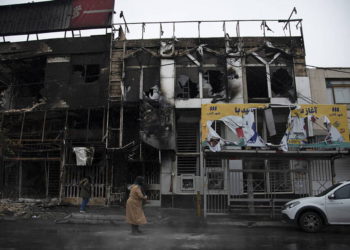 Dos personas caminan el lunes ante edificios quemados durante las protestas, en Teherán. MASOUME ALIAKBAR (AP)