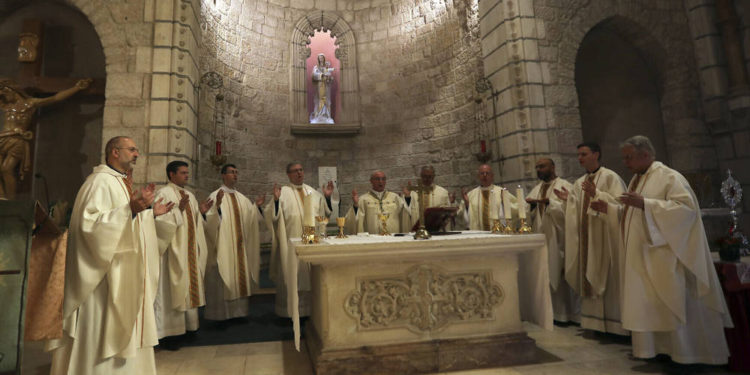 Los clérigos cristianos rezan junto a una reliquia de madera que se cree proviene del pesebre de Jesús en la iglesia de Notre Dame en Jerusalén, el viernes 29 de noviembre de 2019 (AP Photo / Mahmoud Illean)