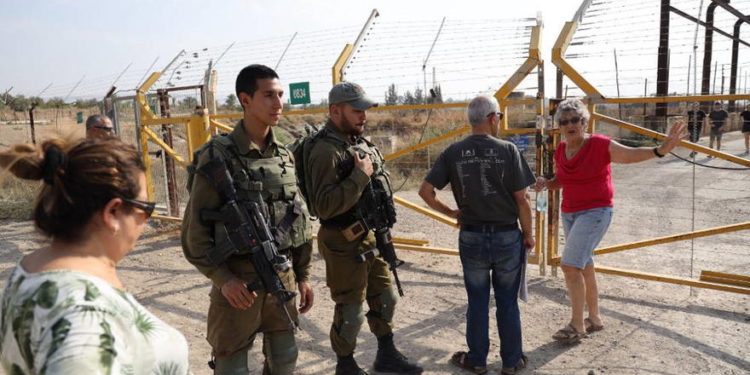 Una fotografía tomada el 8 de noviembre de 2019 muestra a soldados y turistas israelíes junto a una puerta fronteriza en el lado israelí de la frontera en el sitio del valle del Jordán de Naharayim, al este del río Jordán y que ha sido arrendado a Israel como parte de la Tratado de paz entre Israel y Jordania. (MENAHEM KAHANA / AFP)
