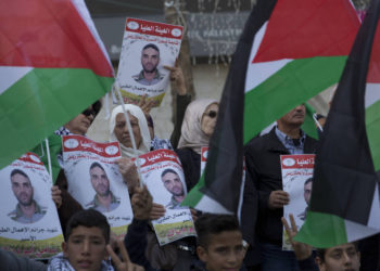 Los manifestantes enarbolan banderas palestinas y llevan carteles con fotos del prisionero palestino en la cárcel israelí, Sami Abu Diak, quien murió de cáncer, durante una protesta en la ciudad cisjordana de Ramallah, el 26 de noviembre de 2019. (AP Photo / Nasser Nasser)