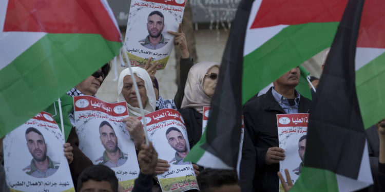 Los manifestantes enarbolan banderas palestinas y llevan carteles con fotos del prisionero palestino en la cárcel israelí, Sami Abu Diak, quien murió de cáncer, durante una protesta en la ciudad cisjordana de Ramallah, el 26 de noviembre de 2019. (AP Photo / Nasser Nasser)