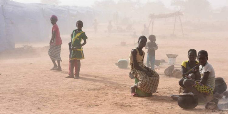 Las personas desplazadas, que huyeron de los ataques de militantes armados en Roffenega, se ven envueltas en polvo mientras se sientan en el campamento construido por la ayuda alemana Ngo HELP en Pissila (crédito de la foto: REUTERS)